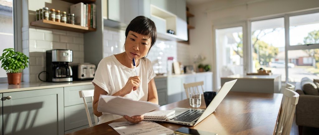 Borrower reviewing student loan forgiveness paperwork on a laptop at a desk