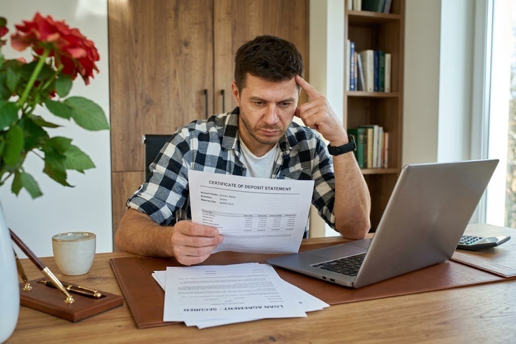 Person reviewing a certificate of deposit statement while considering a loan against fixed deposit
