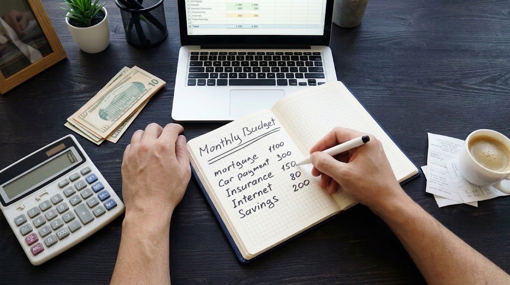 Person planning a monthly budget using the 50/50/50 wealth rule with a notebook and calculator