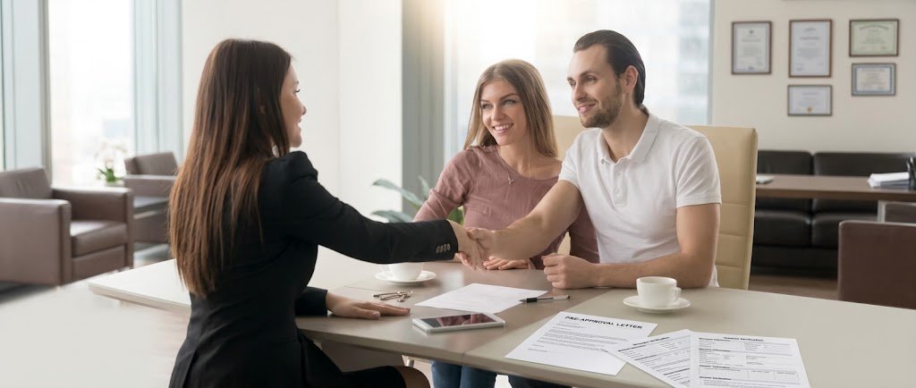 Couple meeting with a loan officer to review mortgage pre-approval paperwork at a desk