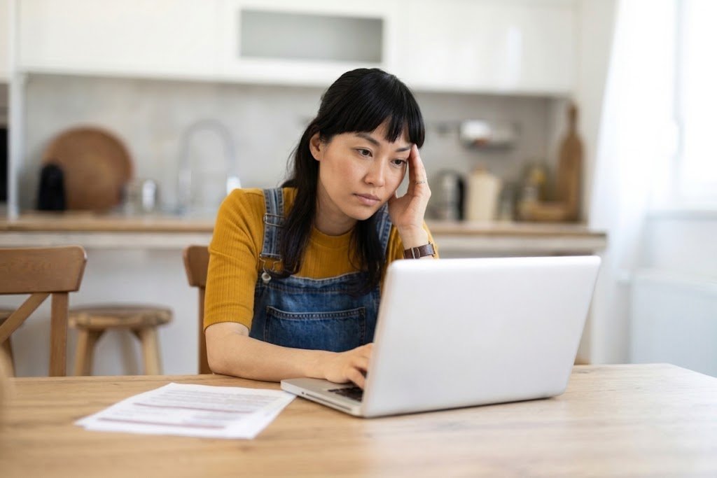 Person reviewing a credit report on a laptop to see how long late payments and collections stay on it