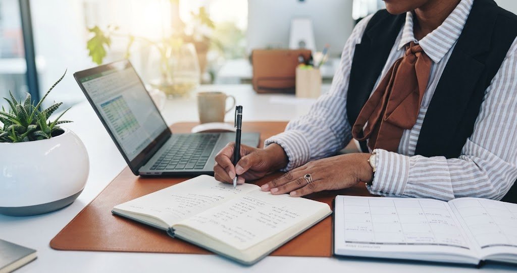 Person planning mini-retirement savings budget at a desk with a laptop and notebook