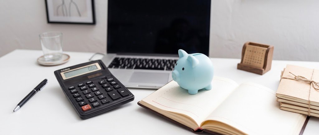 Clean minimalist desk with a notebook and piggy bank illustrating financial minimalism vs frugality