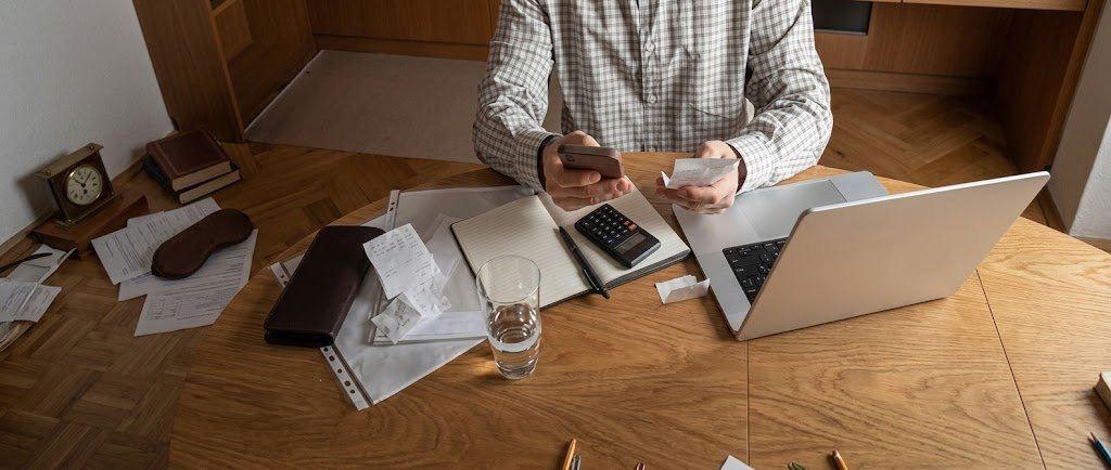 Person comparing credit card debt by age on a statement and laptop at a kitchen table