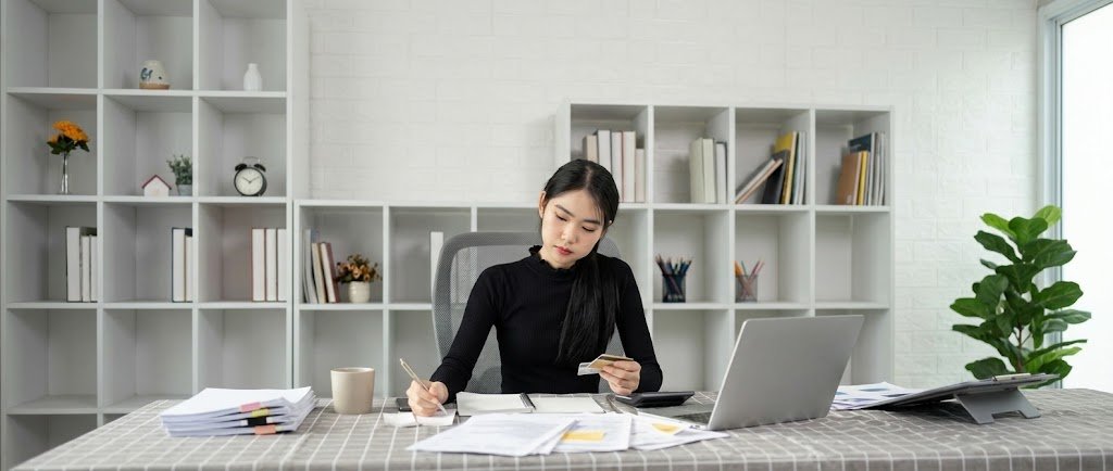 Young woman planning money moves for women on a laptop with a notebook and coffee