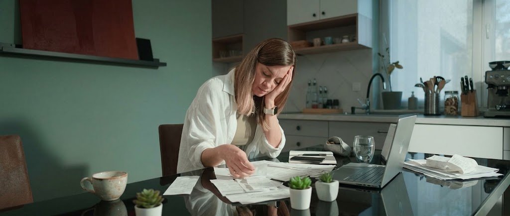 Person reviewing bills and bank statements to avoid the sunk cost fallacy in money decisions